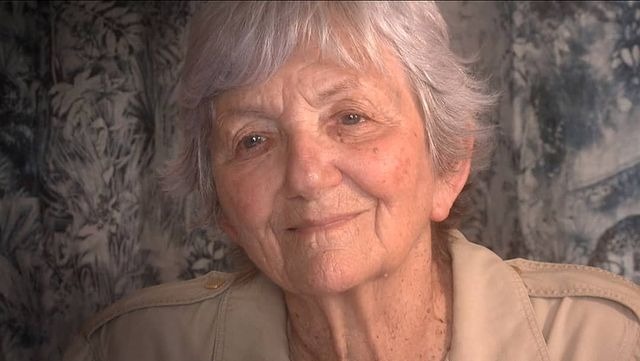 Catherine Hubeau posing for a photo by wearing a brown jacket.